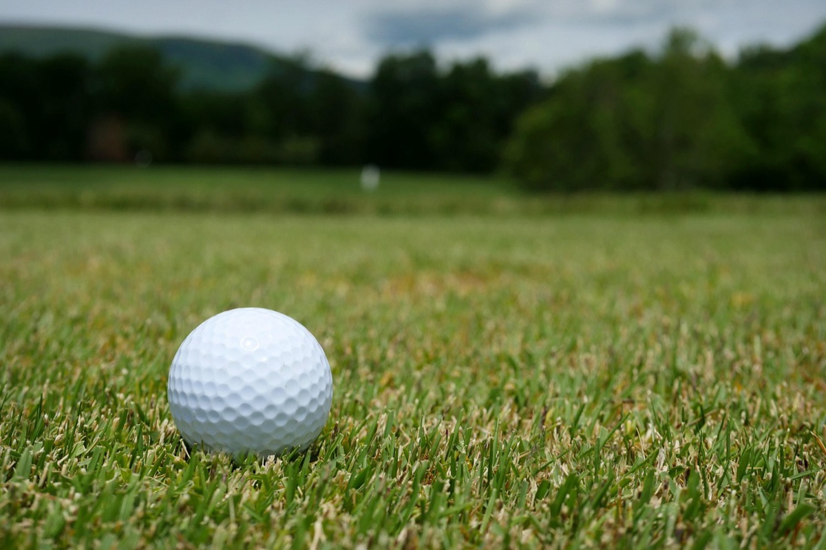 Close-up de uma bola de golfe em um tee no campo.