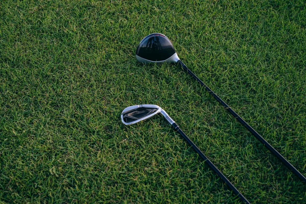 A close-up view of two golf clubs resting on neatly manicured grass, perfect for golf enthusiasts.